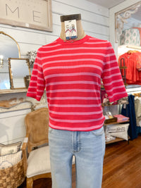 Mannequin wearing a  pink striped sweater top and light blue jeans in a store setting.