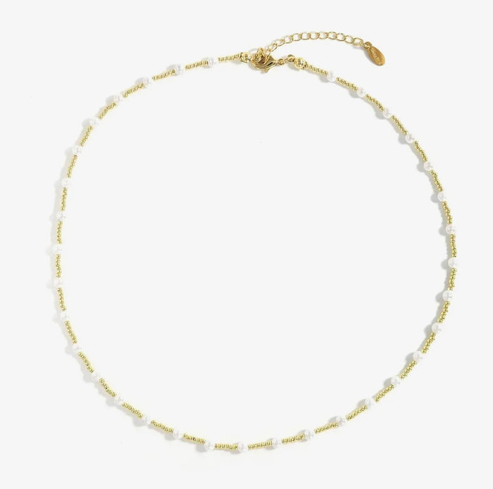Gold and pearl beaded necklace on a white background