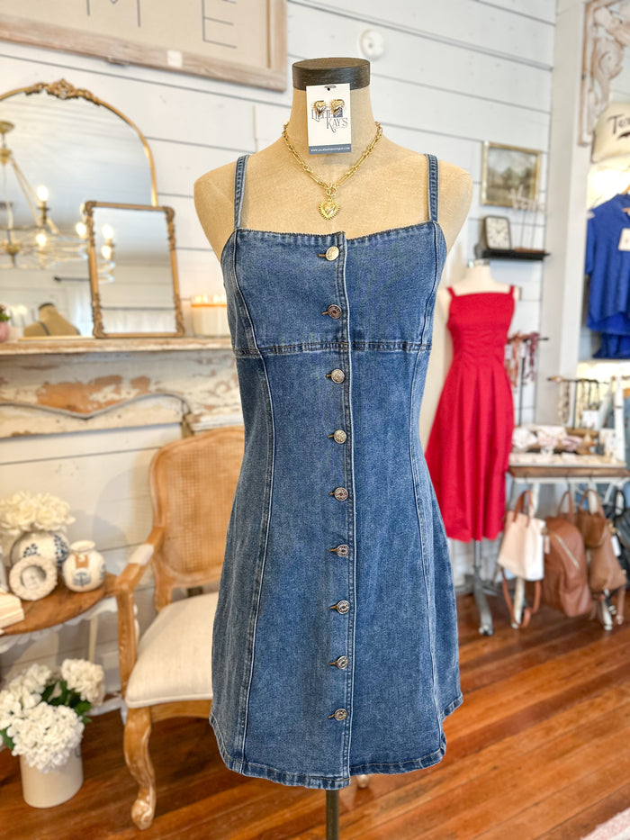 Blue denim dress on a mannequin in a store setting with various items in the background.
