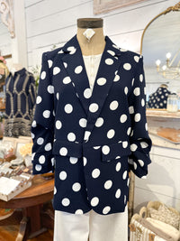 Navy blazer with white polka dots on a mannequin in a store setting.