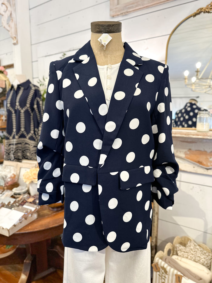 Navy blazer with white polka dots on a mannequin in a store setting.