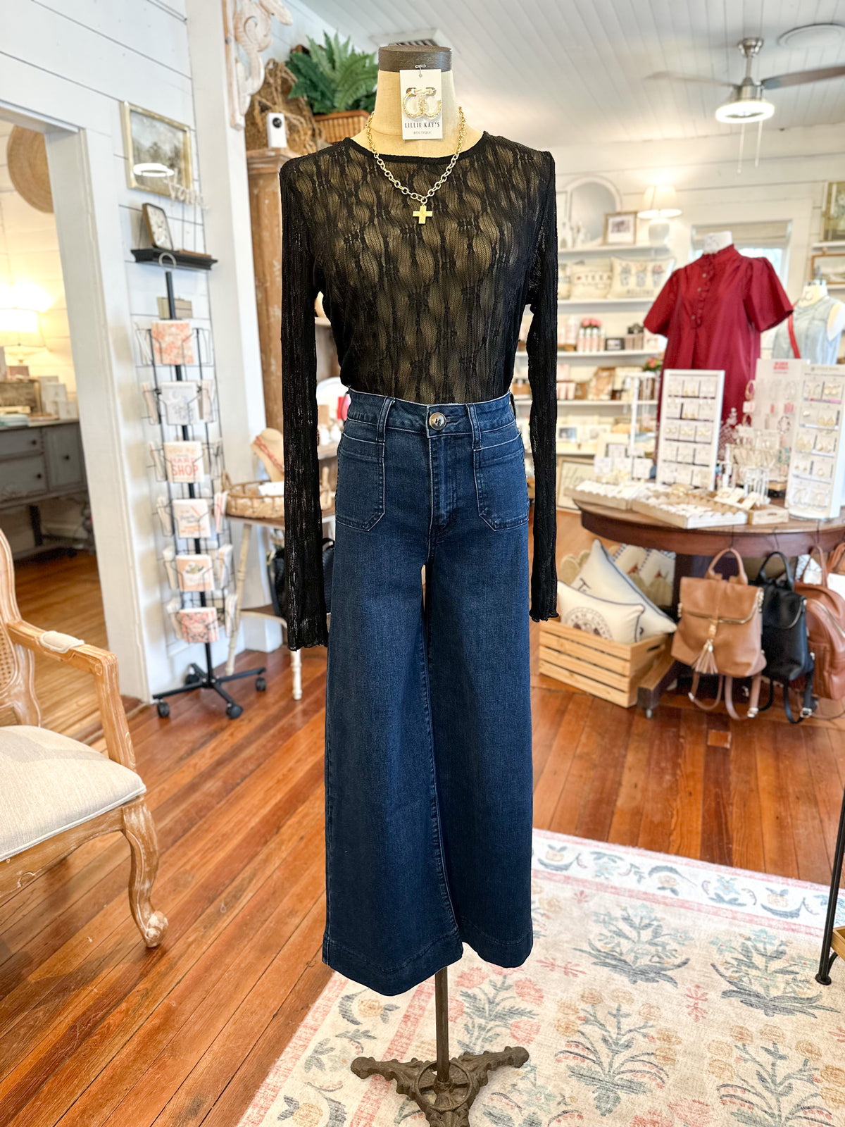 Mannequin wearing a black lace top and blue jeans in a store setting
