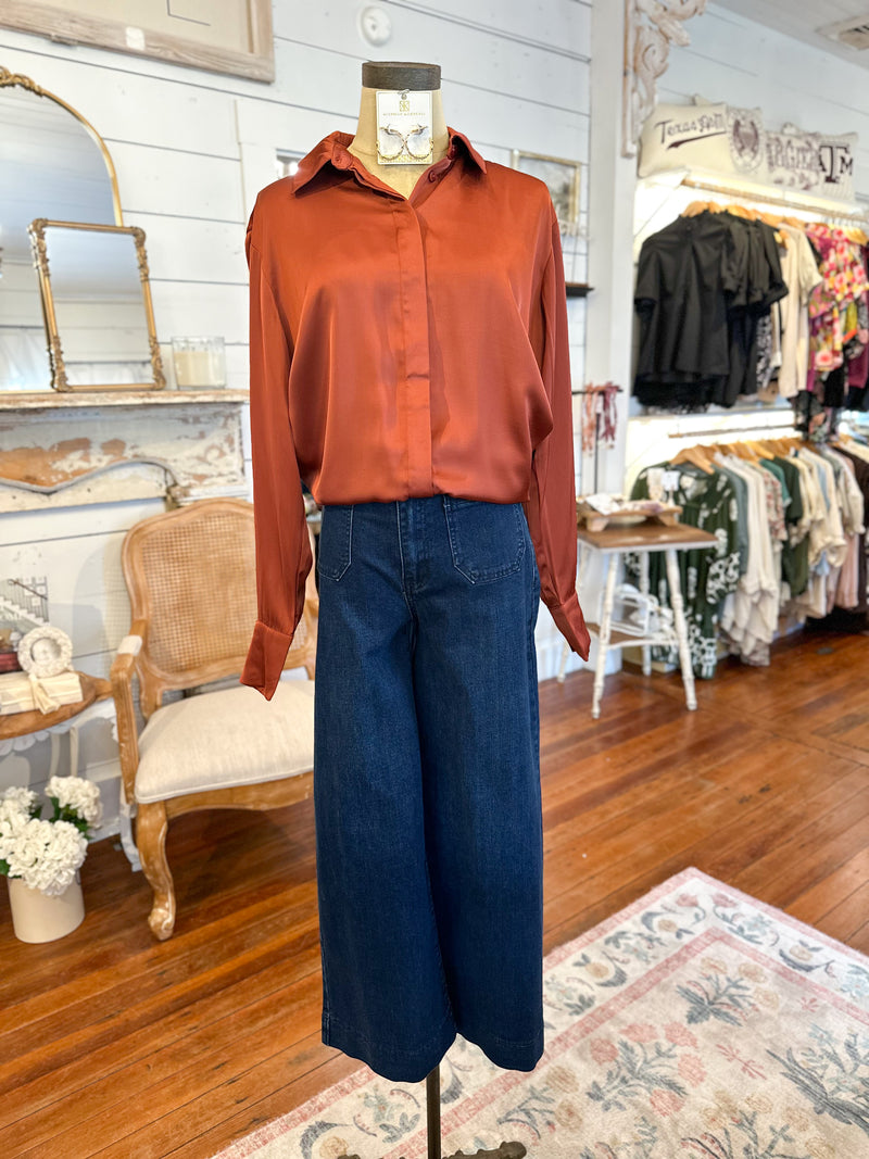 Mannequin wearing a rust-colored blouse and blue jeans in a store setting