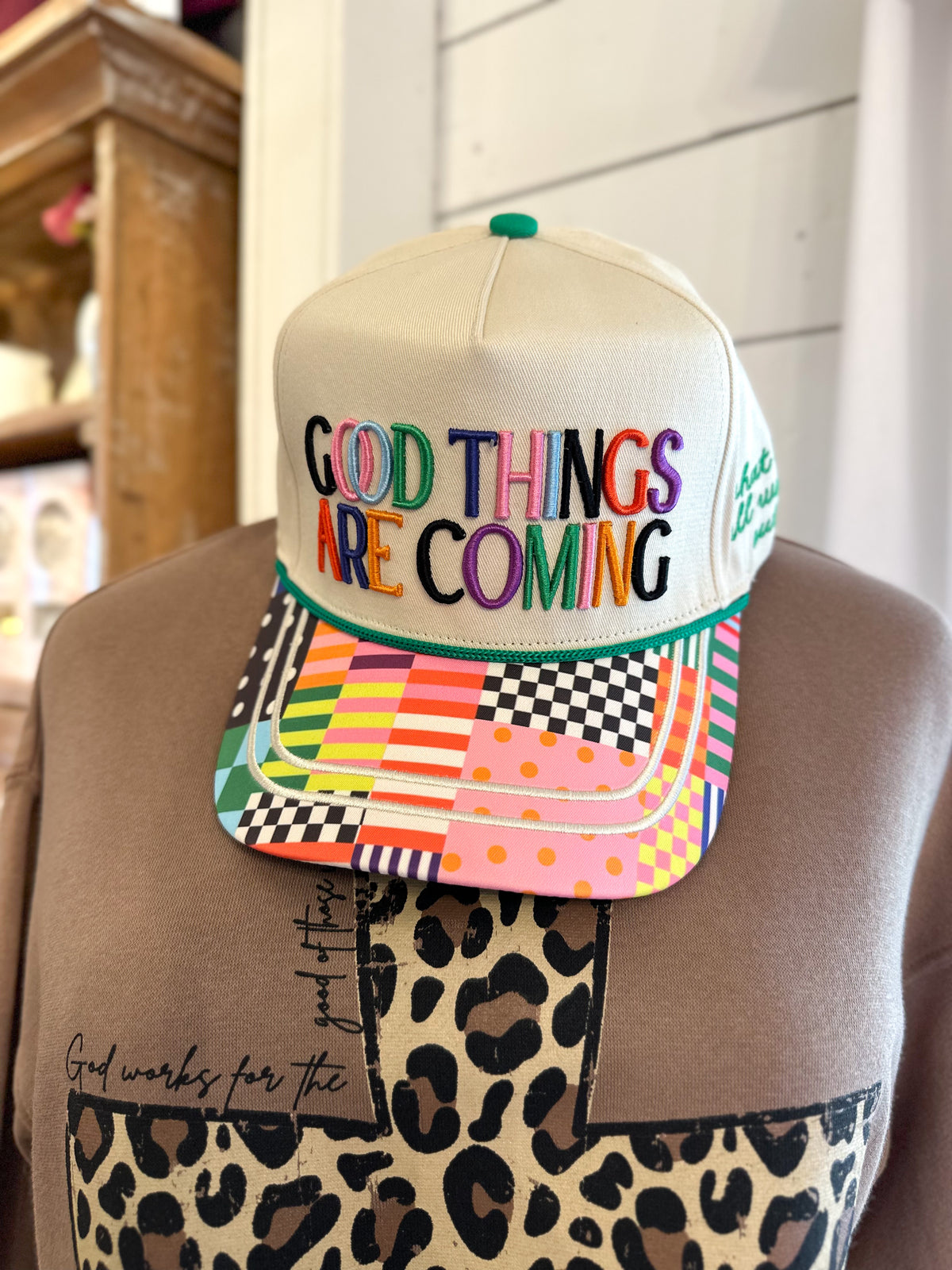 Colorful cap with 'Good Things Are Coming' text on a mannequin head.