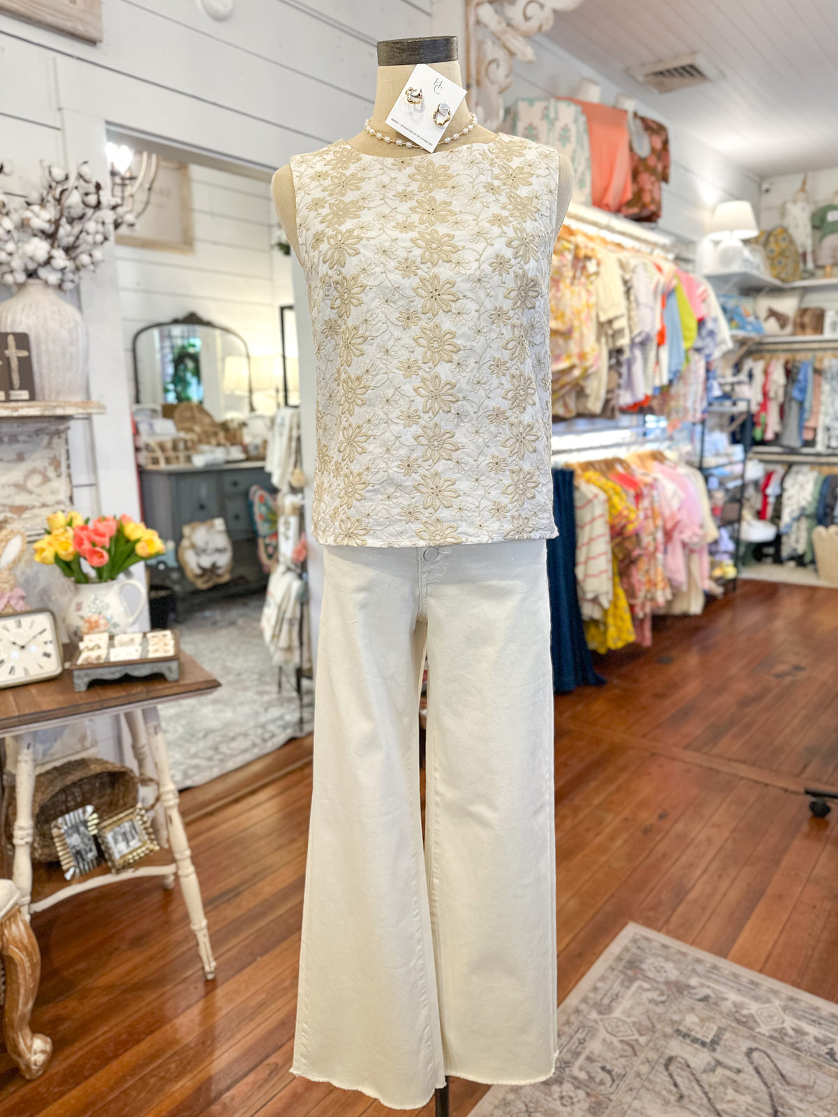Mannequin wearing a cream and tan
 top and white pants in a store setting