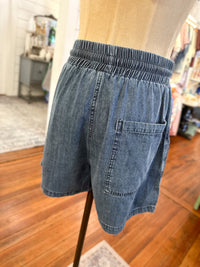 Blue denim shorts on a mannequin against a blurred indoor background