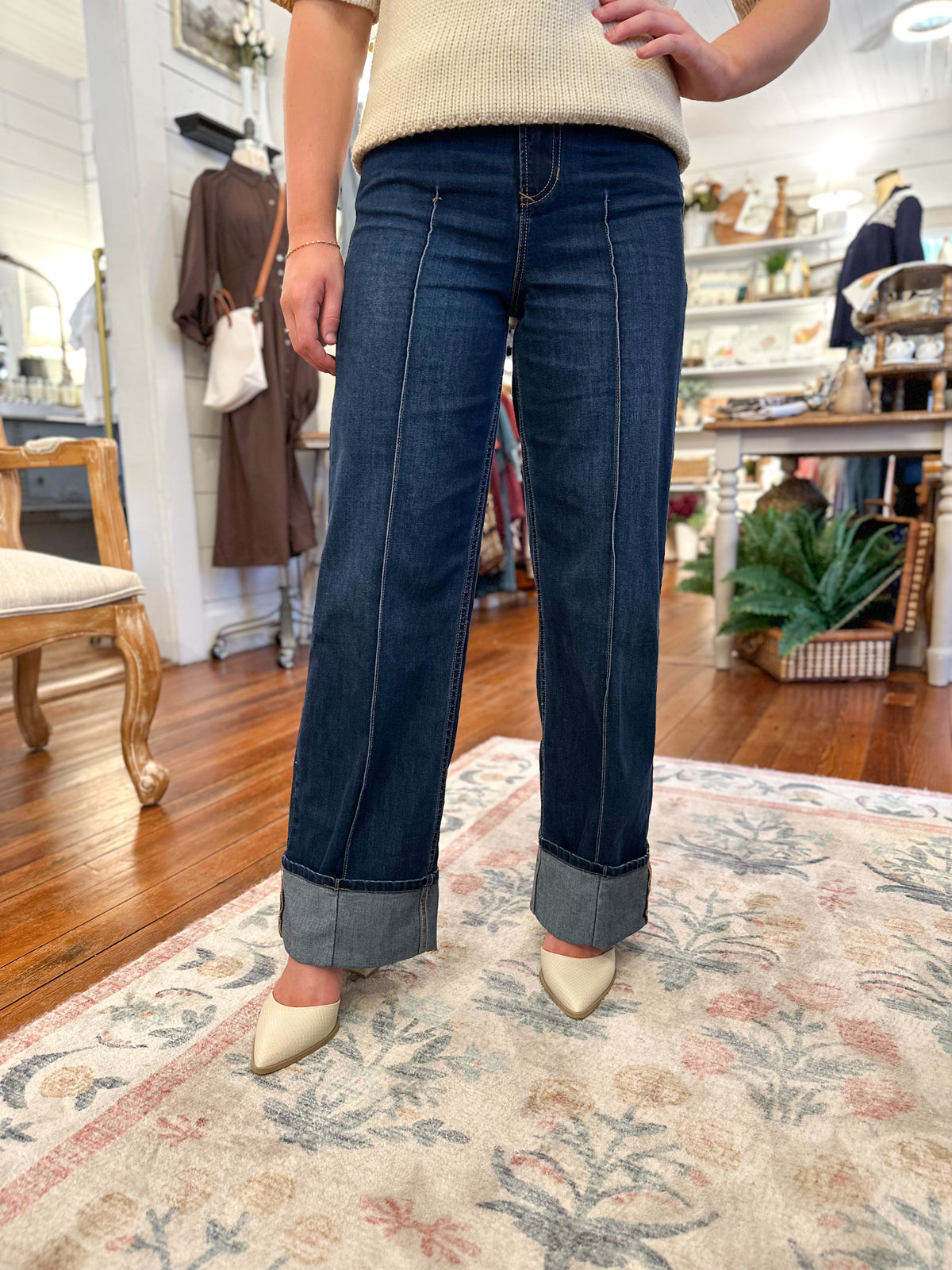 Person wearing blue jeans and a beige sweater in a store setting
