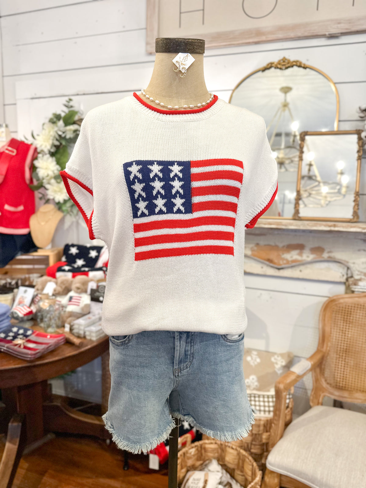 Mannequin wearing a sweater with an American flag design in a store setting.