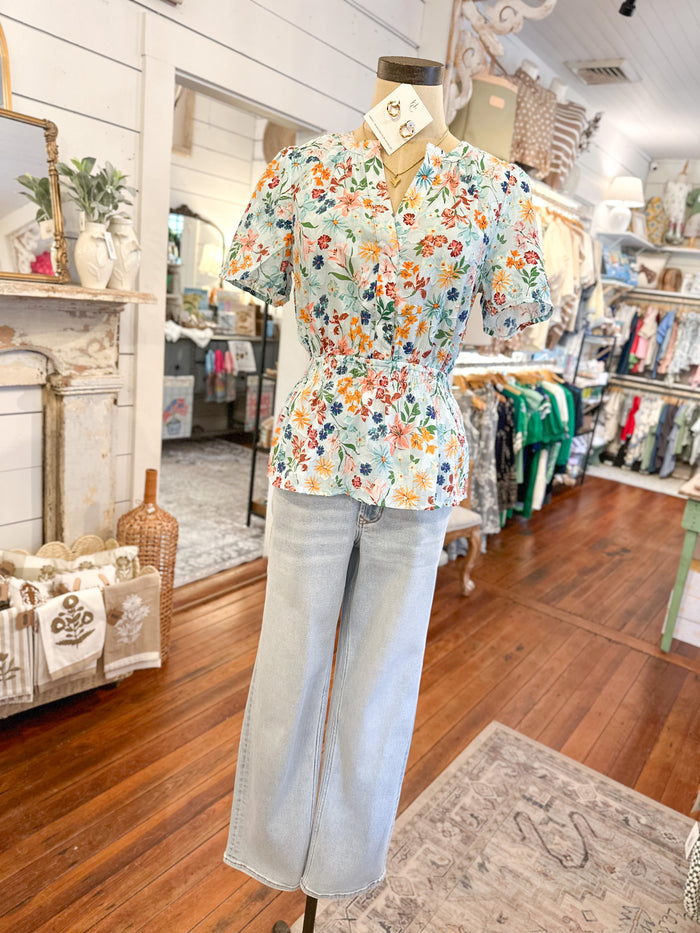 Mannequin wearing a floral blouse and jeans in a store setting
