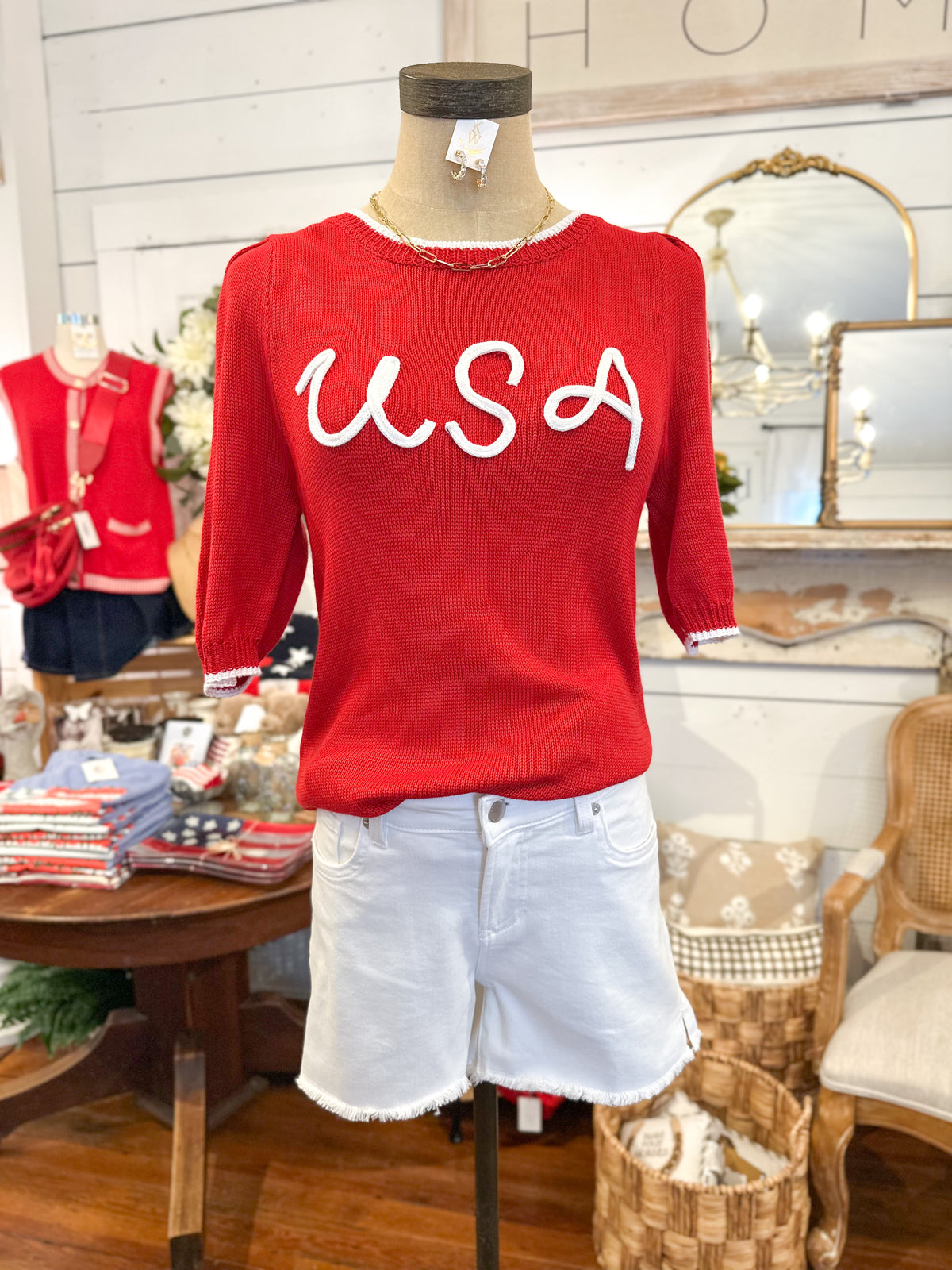 Red sweater with 'USA' text on a mannequin in a store setting