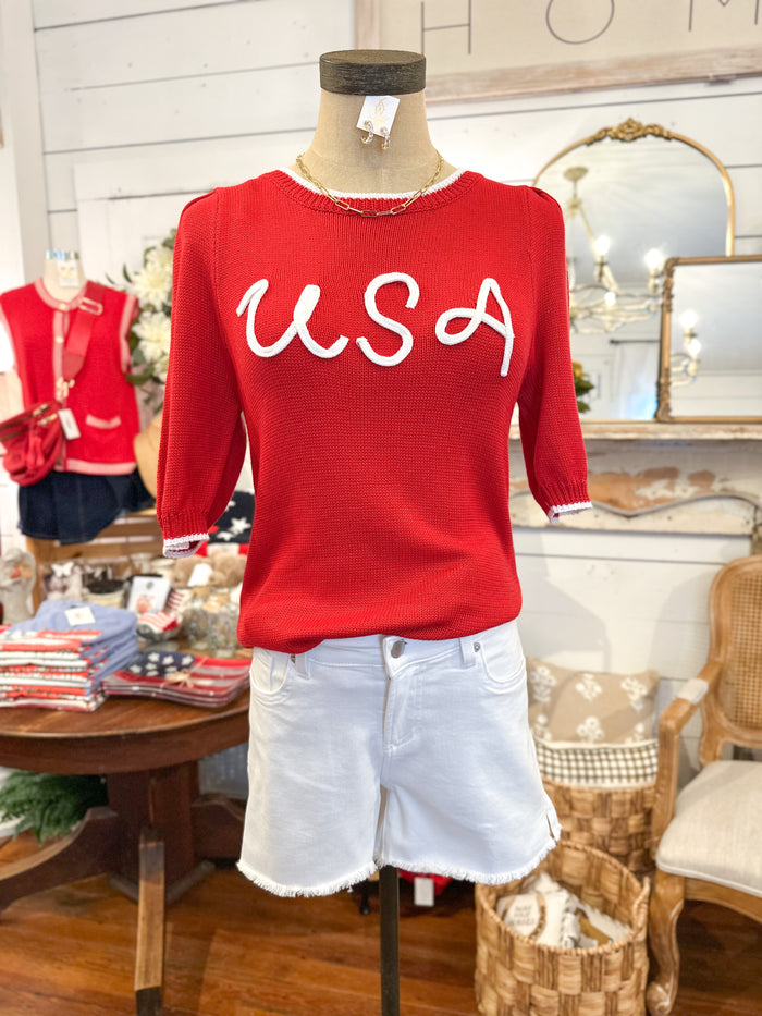 Red sweater with 'USA' text on a mannequin in a store setting