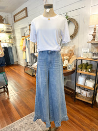 Mannequin wearing a white t-shirt and blue jeans in a store setting.