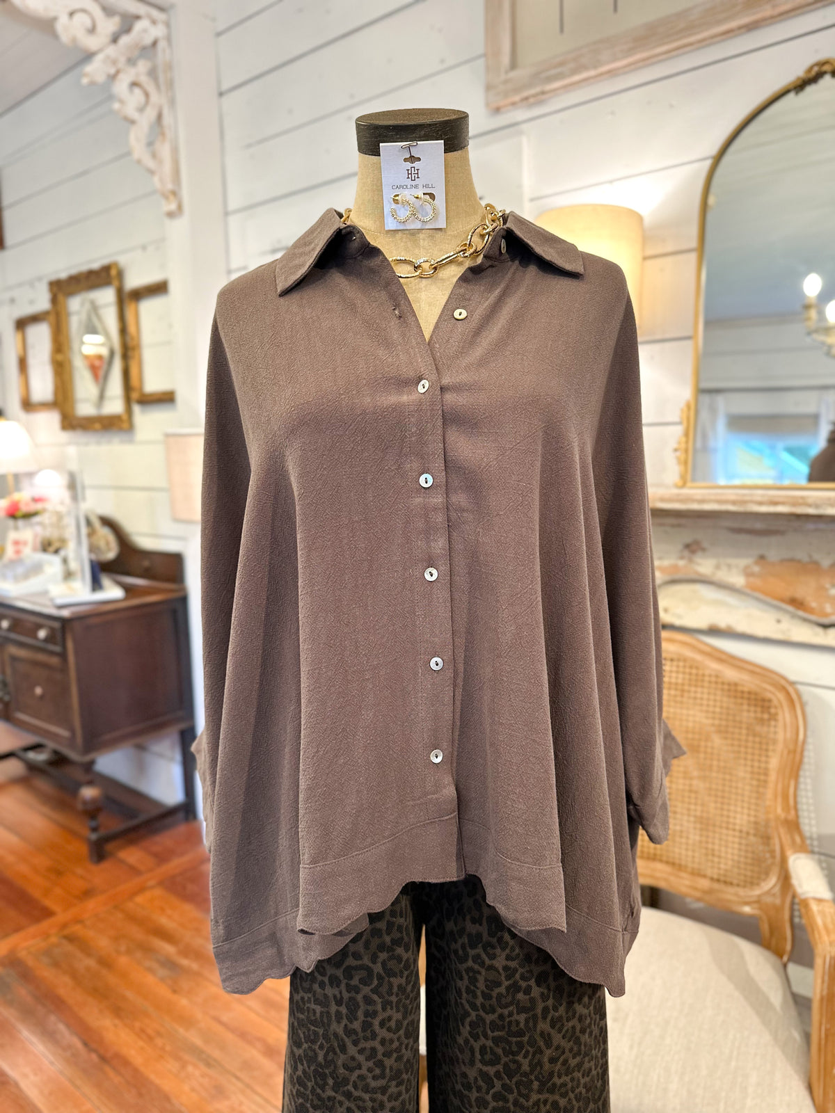 Brown button-up linen blend shirt on a mannequin in a store setting with wooden floor and mirrors.