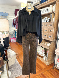 black long sleeve top paired with brown and black printed jeans inside boutiques store 
