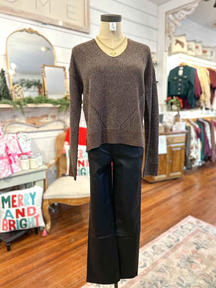 Mannequin wearing a brown sweater and black pants in a store setting with Christmas decorations.