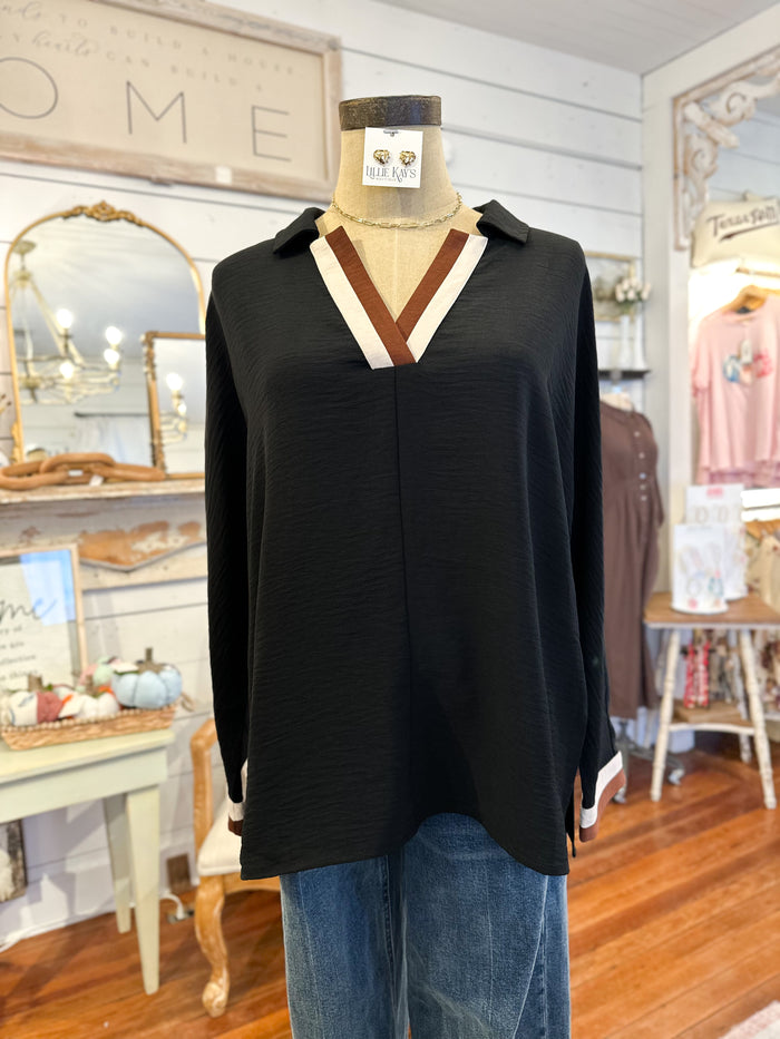 Black long-sleeve top with a V-neck on a mannequin in a store setting.