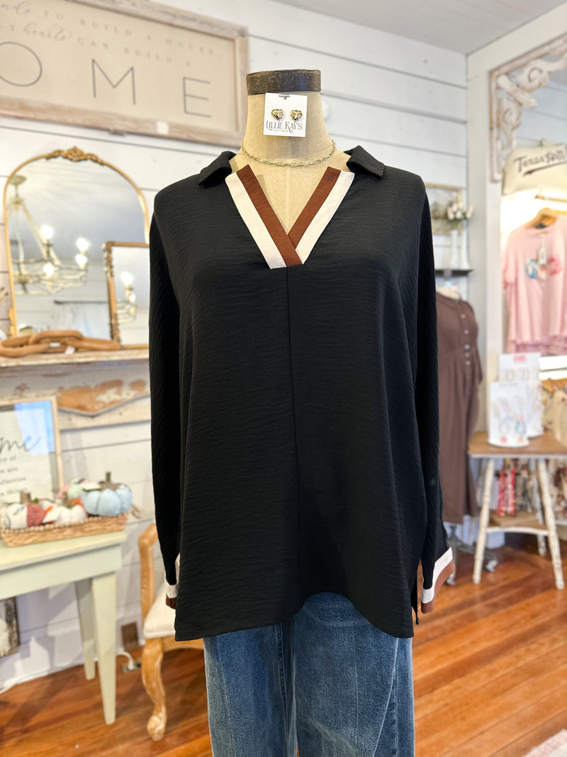 Black long-sleeve top with a V-neck on a mannequin in a store setting.