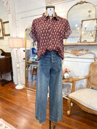 Mannequin wearing a patterned shirt and jeans in a room with wooden floors and mirrors. layerz stevie top 