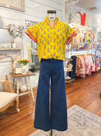 Mannequin wearing a yellow floral blouse and blue pants in a store setting