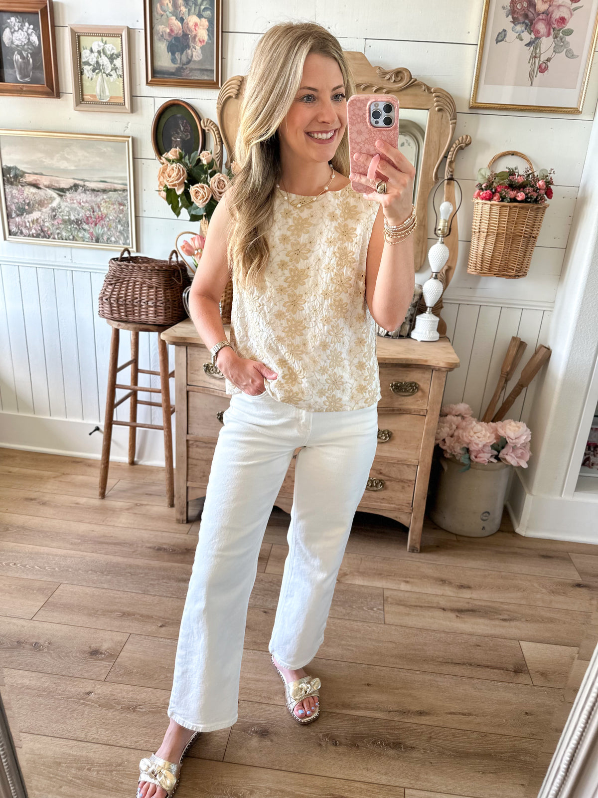 Woman taking a mirror selfie in a room with wooden floors and decorative items.