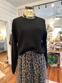 Mannequin wearing a black sweater and leopard print skirt in a store setting