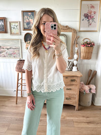 Woman taking a mirror selfie in a room with wooden furniture and decorative items.