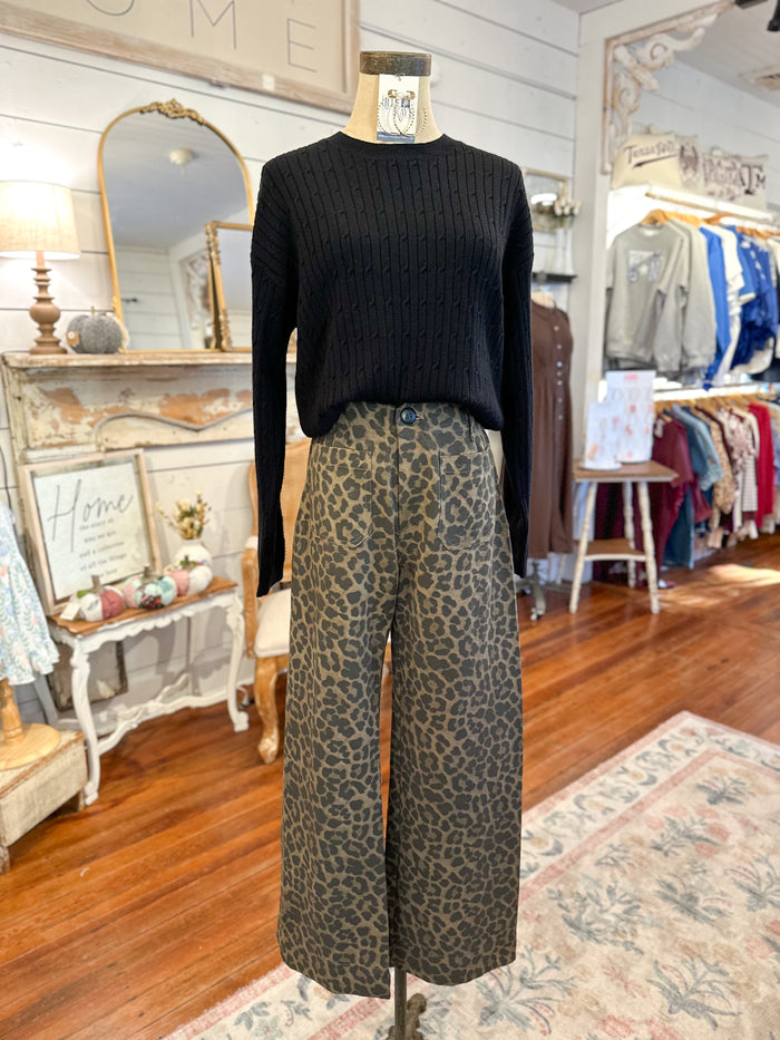 Mannequin wearing a black sweater and leopard print pants in a store setting