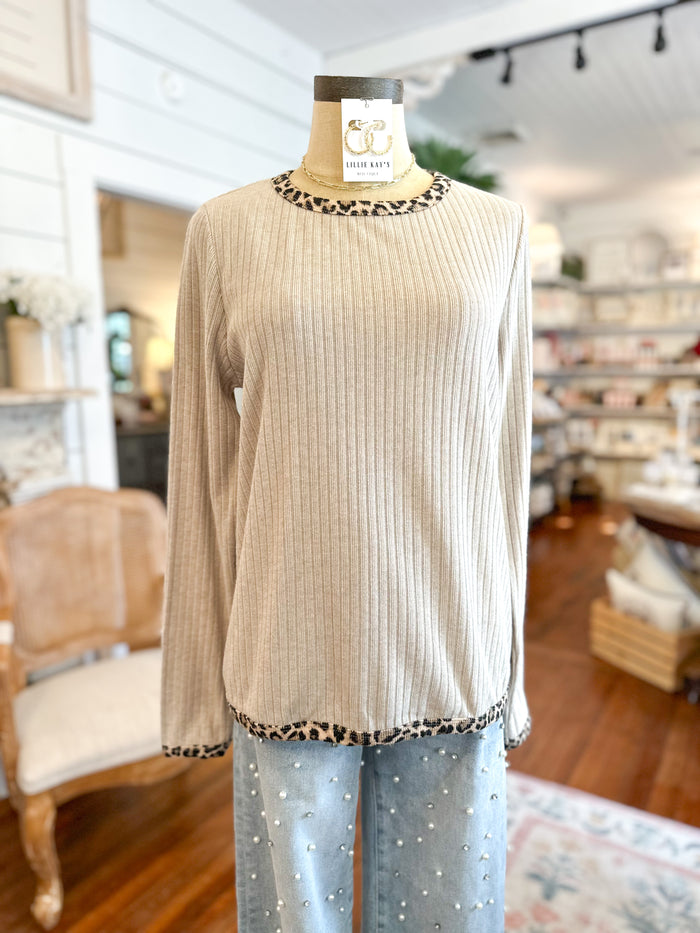 Mannequin wearing a beige ribbed sweater with leopard print trim in a store setting