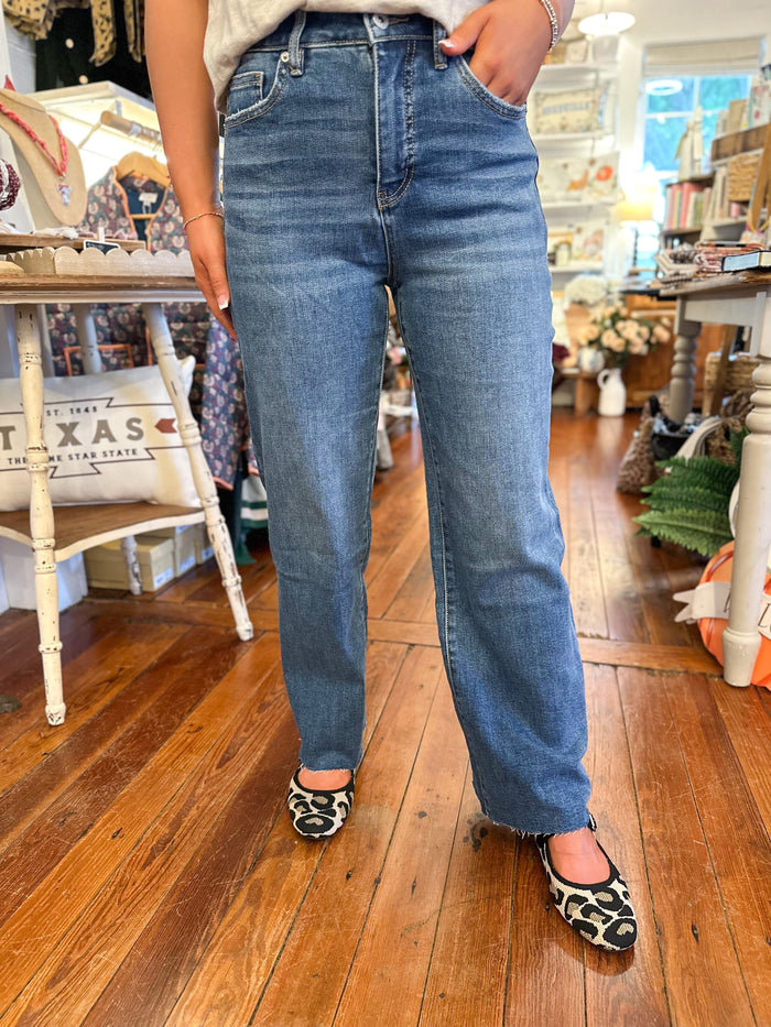 Person wearing blue jeans standing on a wooden floor in a store.