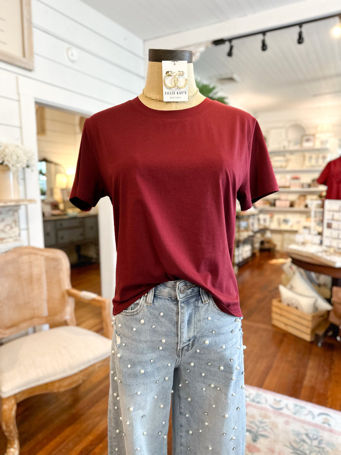 Maroon t-shirt on a mannequin with pearl jeans in a store setting