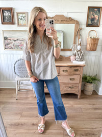Woman taking a selfie in a room with wooden furniture and decorative items. navy blue stripe top