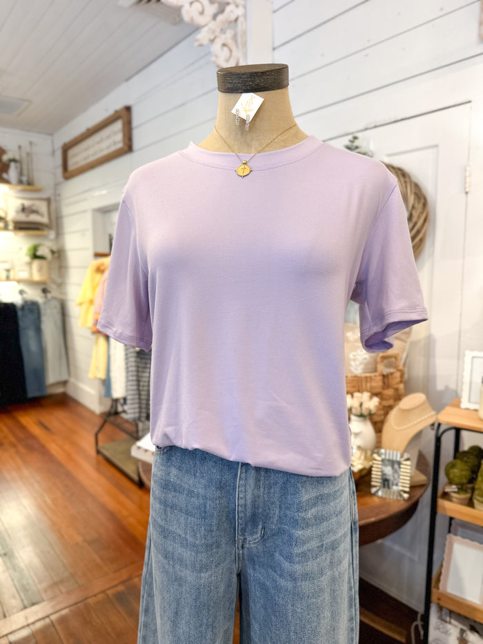 Mannequin wearing a light purple t-shirt and blue jeans in a store setting.
