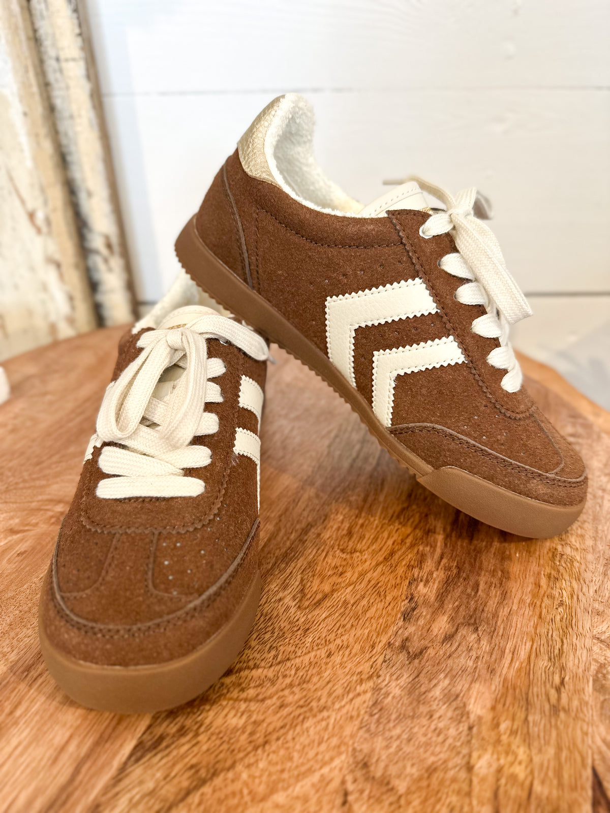 Brown sneakers with white laces and sole on a wooden surface yellowbox neevan 
