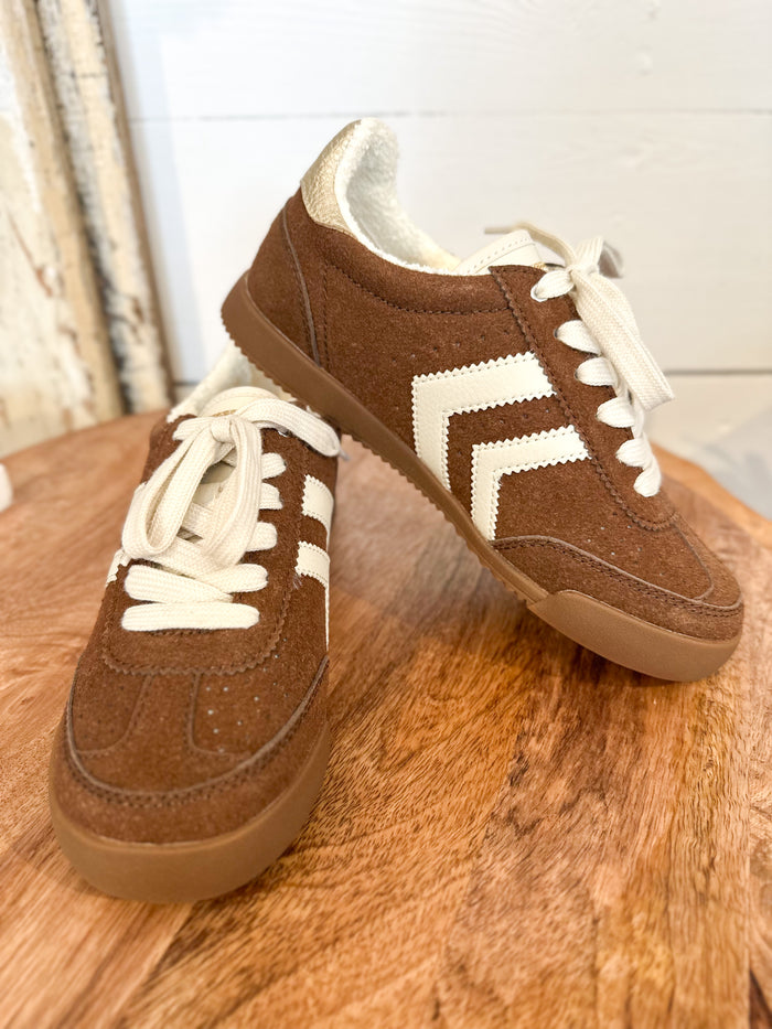 Brown sneakers with white laces and sole on a wooden surface yellowbox neevan 
