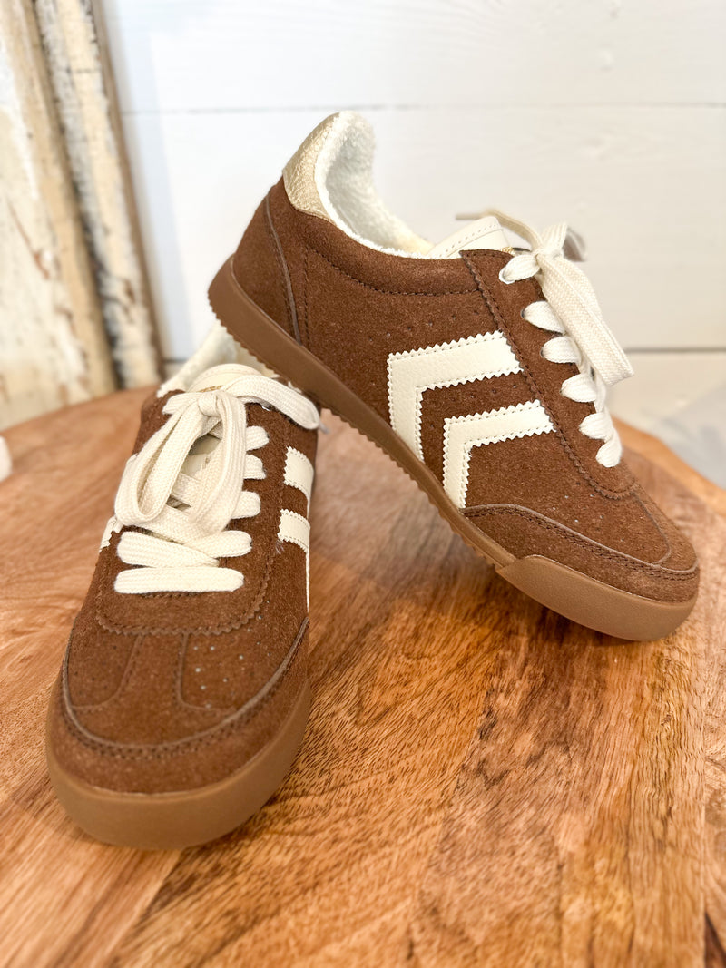 Brown sneakers with white laces and sole on a wooden surface yellowbox neevan 
