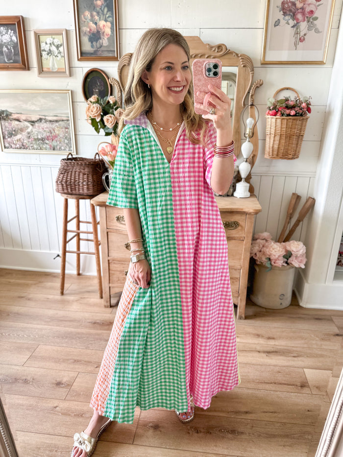 Woman taking a mirror selfie wearing a colorful checkered dress in a home setting.