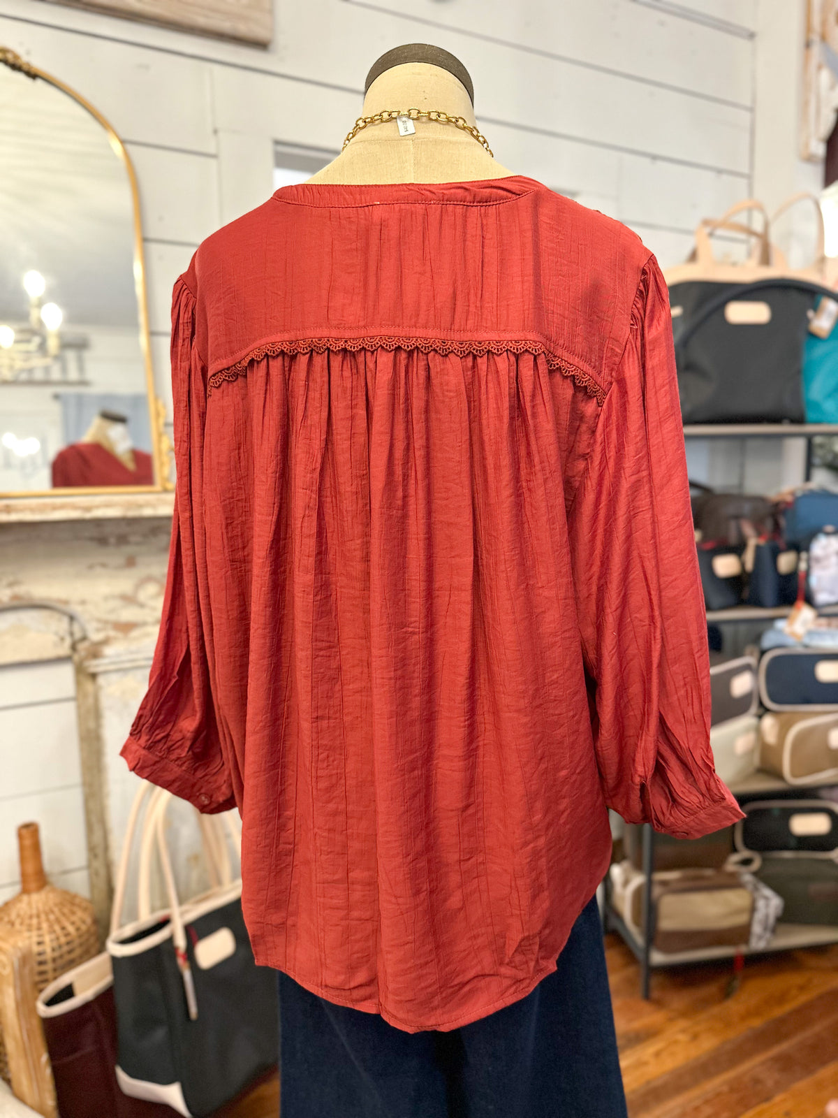 back of rust color umgee blouse inside store setting 