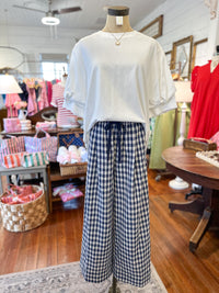 Mannequin wearing a white blouse and blue checkered pants in a store setting.