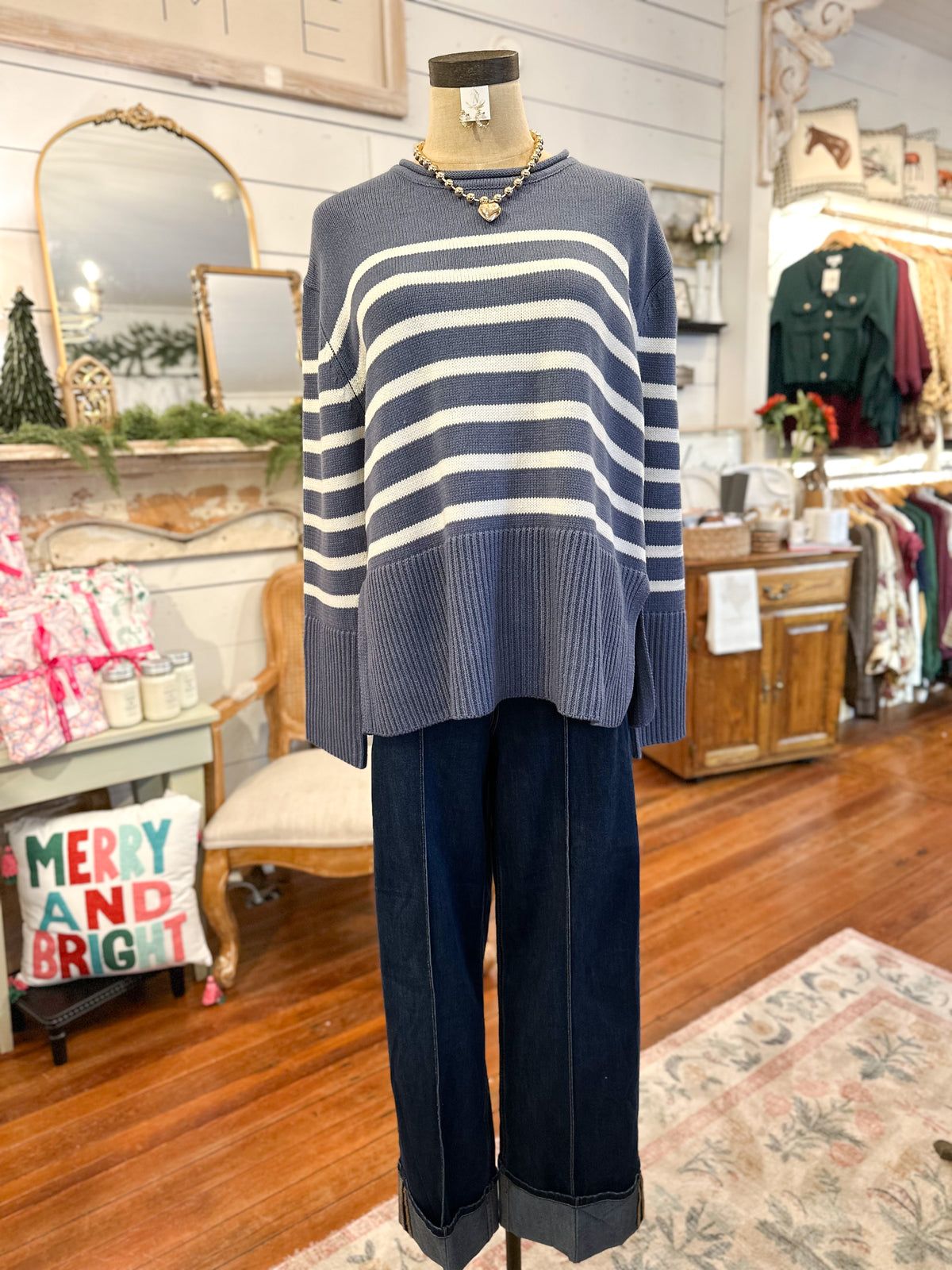 Mannequin wearing a blue and white striped sweater and dark pants in a store setting.