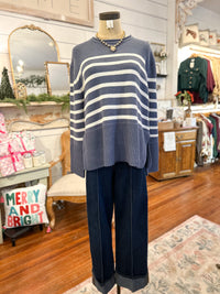 Mannequin wearing a blue and white striped sweater and dark pants in a store setting.