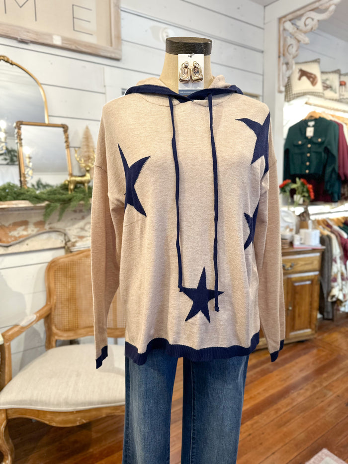 Mannequin wearing a beige sweater with navy star patterns in a store setting.