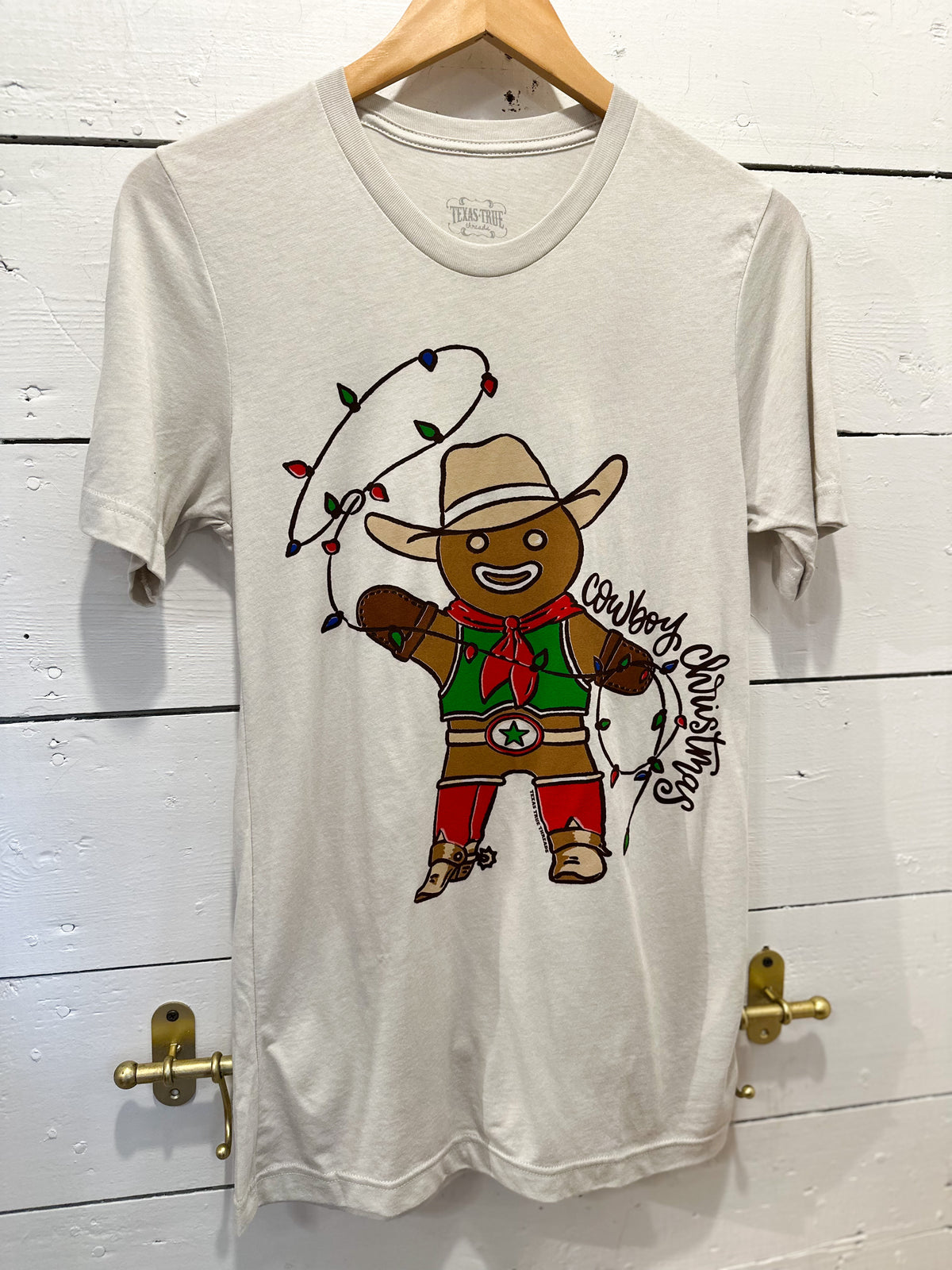 Gray t-shirt with a cowboy graphic on a wooden door