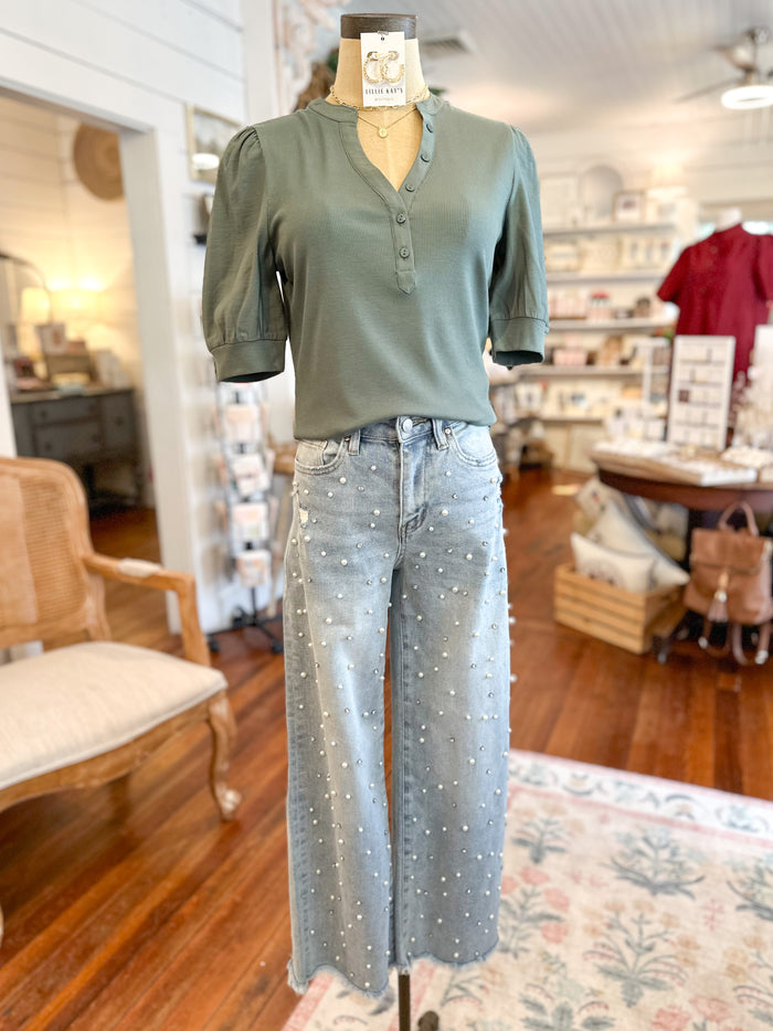 Mannequin wearing a green top and studded jeans in a store setting