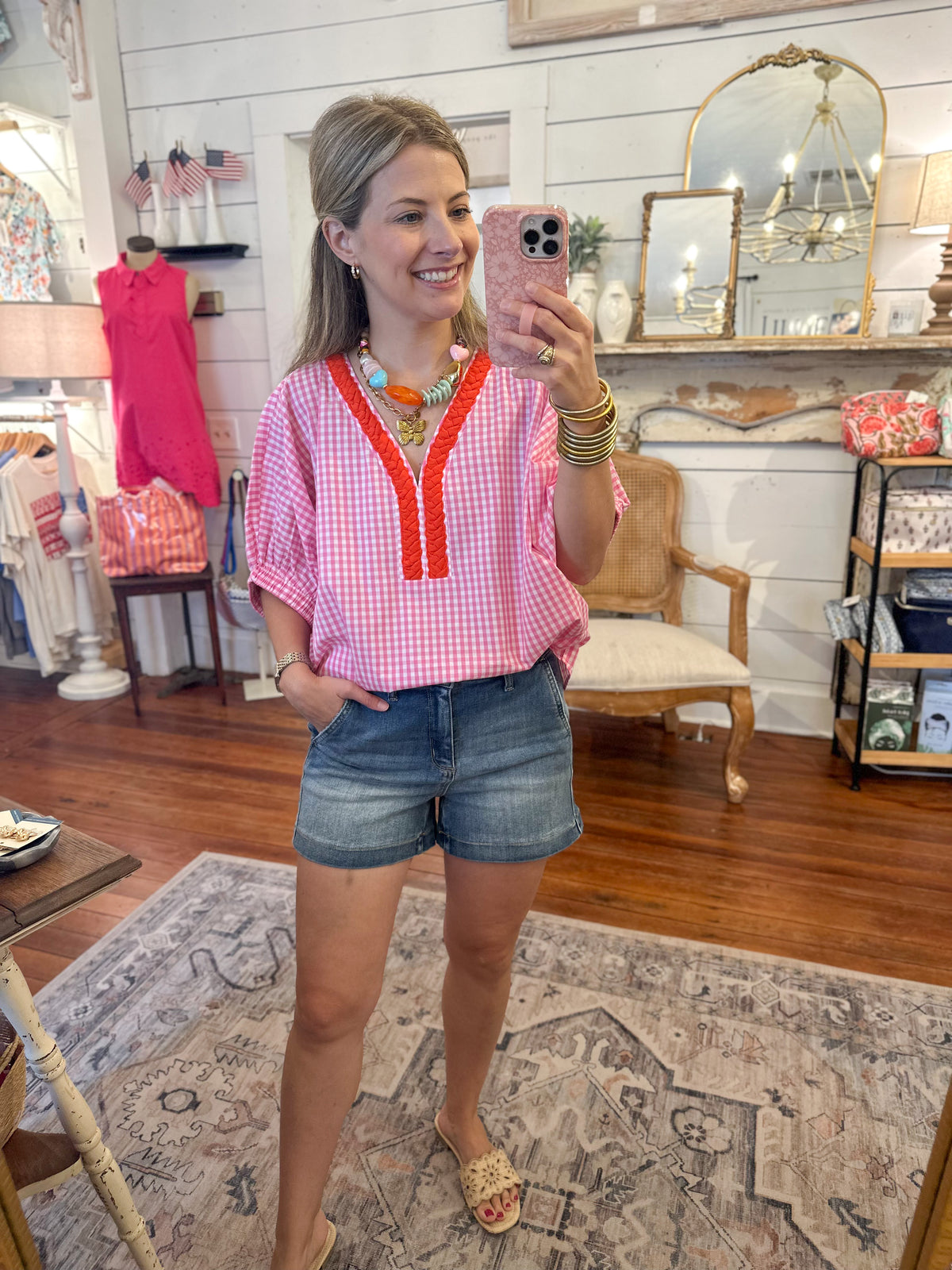 Woman taking a mirror selfie in a room with decor and furniture.