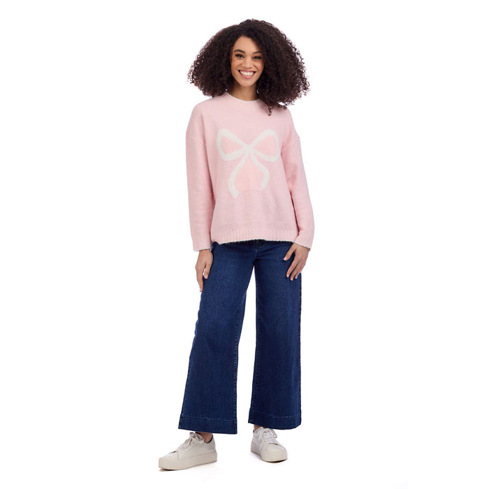 Woman wearing a pink sweater with a white design and blue jeans on a white background