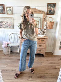 Woman taking a mirror selfie wearing an olive green shirt and blue jeans in a home setting. dear john lasso barrel jean 