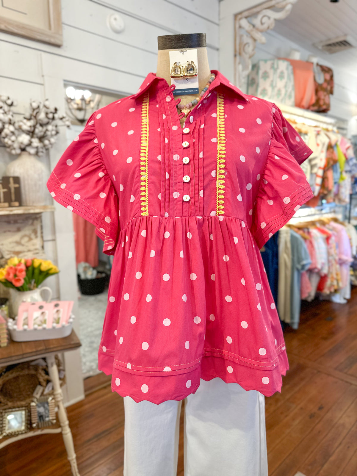 Pink polka dot blouse on a mannequin in a store setting