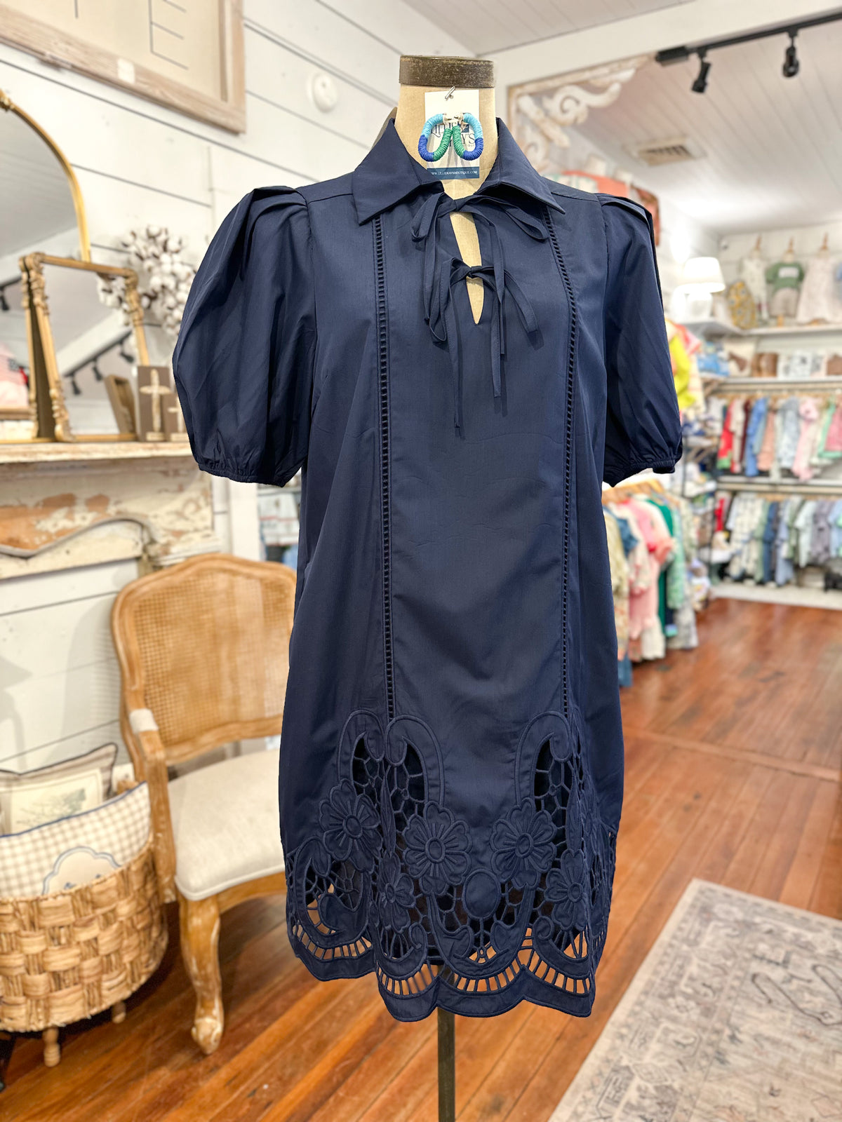 Navy blue dress with lace details on a mannequin in a store setting.
