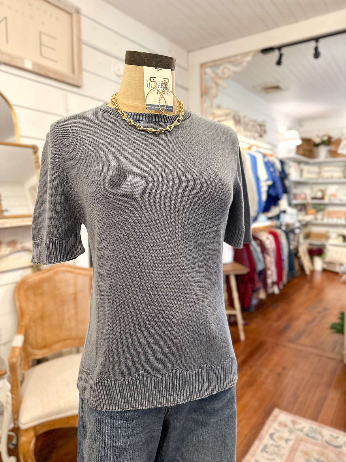 dusty blue  sweater on a mannequin in a store setting with various items in the background