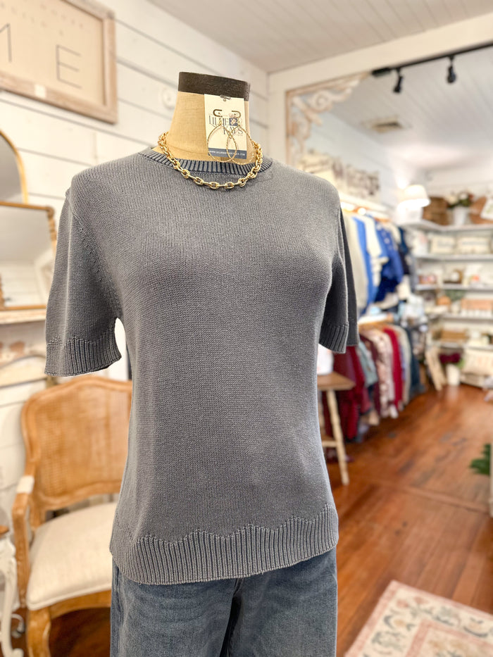 dusty blue  sweater on a mannequin in a store setting with various items in the background